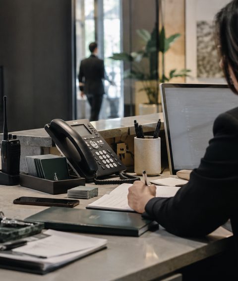 A hotel front desk workstation during a shift: radio, phone, guest notes, key cards and a screen